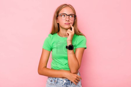 Foto de Caucásico adolescente chica aislado en rosa fondo contemplando, la planificación de una estrategia, pensando en la forma de un negocio. - Imagen libre de derechos