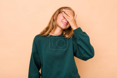 Téléchargez les photos : Fille adolescente caucasienne isolée sur fond beige rit en gardant joyeusement les mains sur la tête. Concept de bonheur. - en image libre de droit