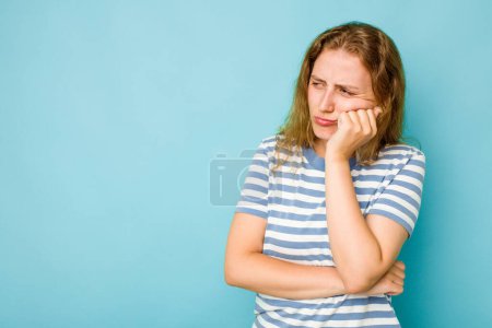 Foto de Mujer caucásica joven aislada sobre fondo azul que se siente triste y pensativa, mirando espacio de copia. - Imagen libre de derechos