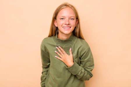 Photo for Caucasian teen girl isolated on beige background laughs out loudly keeping hand on chest. - Royalty Free Image