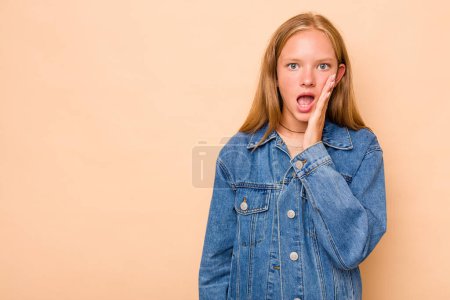 Photo for Caucasian teen girl isolated on beige background shouts loud, keeps eyes opened and hands tense. - Royalty Free Image