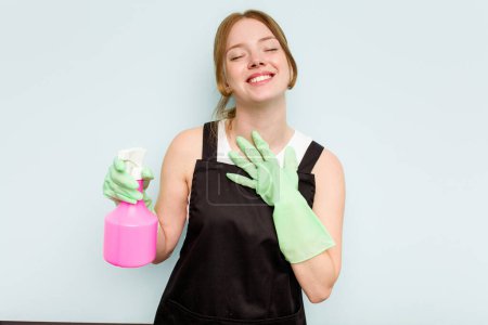 Photo for Young cleaner woman isolated on blue background laughs out loudly keeping hand on chest. - Royalty Free Image