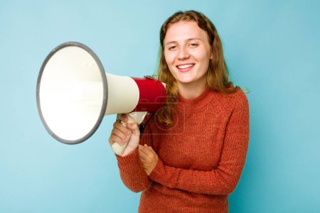 Téléchargez les photos : Jeune femme caucasienne tenant mégaphone isolé sur fond bleu riant et s'amusant. - en image libre de droit