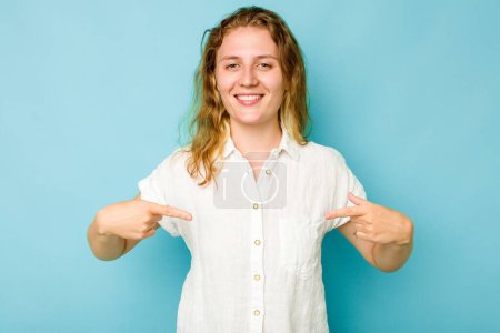 Photo for Young caucasian woman isolated on blue background person pointing by hand to a shirt copy space, proud and confident - Royalty Free Image