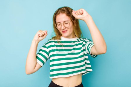 Photo for Young caucasian woman isolated on blue background celebrating a special day, jumps and raise arms with energy. - Royalty Free Image