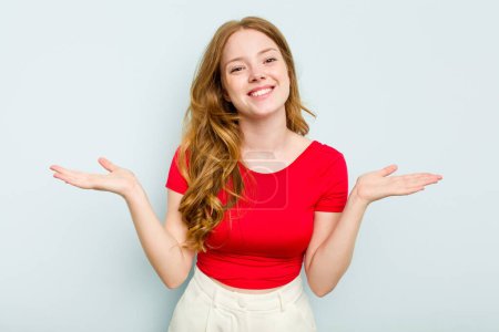 Photo for Young caucasian woman isolated on blue background makes scale with arms, feels happy and confident. - Royalty Free Image