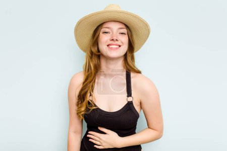 Foto de Joven mujer caucásica que va a la playa aislada sobre fondo azul riendo y divirtiéndose. - Imagen libre de derechos