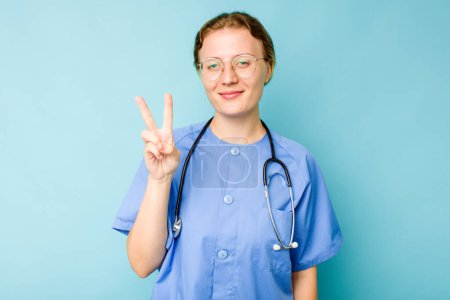 Foto de Joven enfermera caucásica aislada sobre fondo azul mostrando el número dos con los dedos. - Imagen libre de derechos