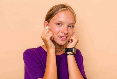 Foto de Pequeña chica caucásica escuchando música aislada sobre fondo beige - Imagen libre de derechos