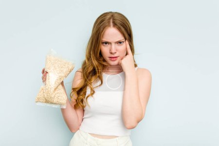 Photo for Young caucasian woman holding oatmeal isolated on blue background showing a disappointment gesture with forefinger. - Royalty Free Image