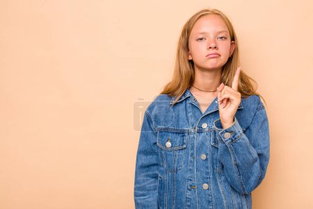 Photo for Caucasian teen girl isolated on beige background showing number one with finger. - Royalty Free Image