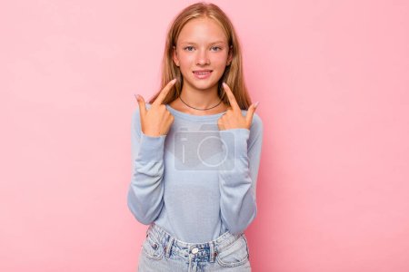 Photo for Caucasian teen girl isolated on pink background smiles, pointing fingers at mouth. - Royalty Free Image