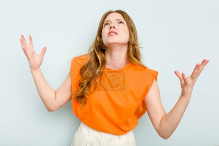 Photo for Young caucasian woman isolated on blue background screaming to the sky, looking up, frustrated. - Royalty Free Image