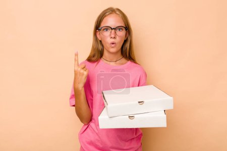 Téléchargez les photos : Petite fille caucasienne tenant une pizza isolée sur fond beige ayant une bonne idée, concept de créativité. - en image libre de droit