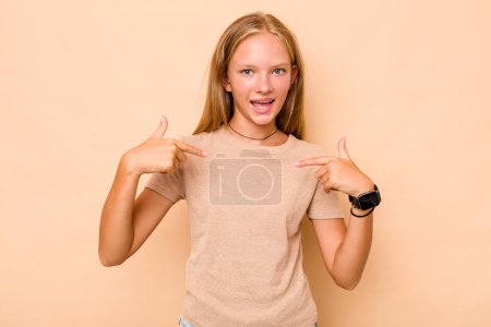 Téléchargez les photos : Caucasienne adolescent fille isolé sur fond beige surpris pointant du doigt, souriant largement. - en image libre de droit