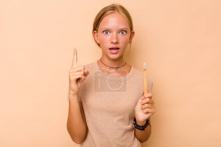 Téléchargez les photos : Caucasien adolescent fille brossage dents isolé sur fond beige ayant une idée, concept d'inspiration. - en image libre de droit