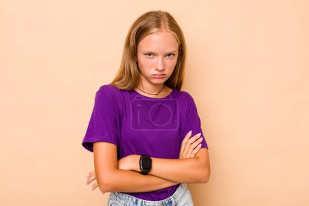 Téléchargez les photos : Caucasien adolescent fille isolé sur beige fond fronçant les sourcils visage dans le mécontentement, garde les bras pliés. - en image libre de droit