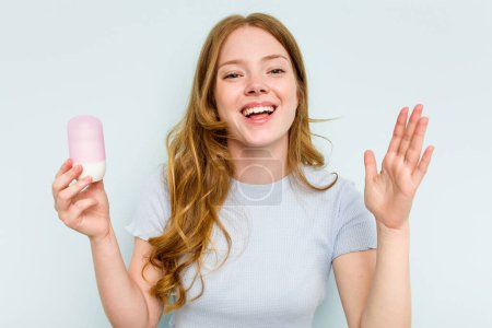 Photo for Young caucasian woman holding deodorant isolated on blue background receiving a pleasant surprise, excited and raising hands. - Royalty Free Image