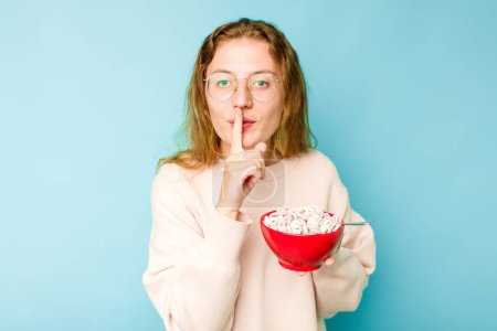 Photo for Young caucasian woman holding a bowl of cereals isolated on blue background keeping a secret or asking for silence. - Royalty Free Image