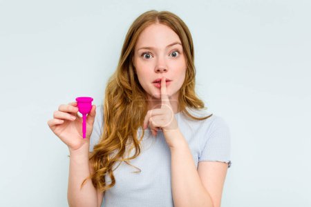 Photo for Young caucasian woman holding menstrual cup isolated on blue background keeping a secret or asking for silence. - Royalty Free Image