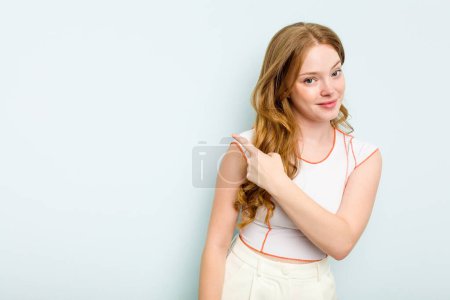 Téléchargez les photos : Jeune femme caucasienne isolée sur fond bleu souriant et pointant du doigt, montrant quelque chose à vide. - en image libre de droit