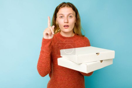 Photo for Young caucasian woman holding pizzas boxes isolated on blue background having some great idea, concept of creativity. - Royalty Free Image