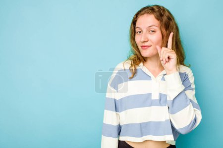 Foto de Mujer joven caucásica aislada sobre fondo azul mostrando el número uno con el dedo. - Imagen libre de derechos