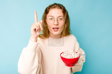 Photo for Young caucasian woman holding a bowl of cereals isolated on blue background having an idea, inspiration concept. - Royalty Free Image