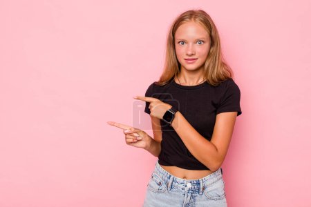Foto de Caucásico adolescente chica aislado en rosa fondo impactado señalando con los dedos índice a un espacio de copia. - Imagen libre de derechos