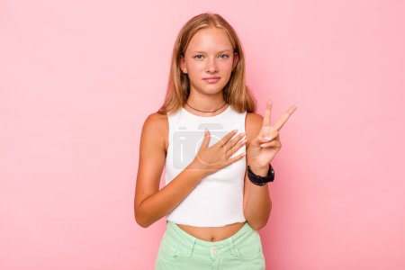 Téléchargez les photos : Caucasien adolescent fille isolé sur fond rose prendre un serment, mettre la main sur la poitrine. - en image libre de droit