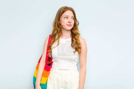 Photo for Young caucasian woman holding LGTBI bag isolated on blue background confused, feels doubtful and unsure. - Royalty Free Image