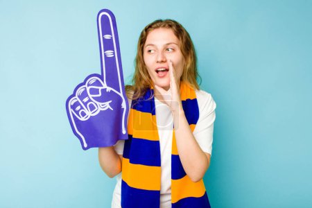 Photo for Young caucasian sports fan woman isolated on blue background is saying a secret hot braking news and looking aside - Royalty Free Image