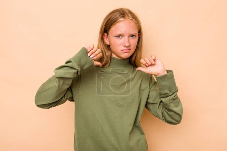 Foto de Caucásico adolescente chica aislado en beige fondo mostrando pulgar hacia abajo, decepción concepto. - Imagen libre de derechos