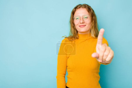 Foto de Mujer joven caucásica aislada sobre fondo azul mostrando el número uno con el dedo. - Imagen libre de derechos