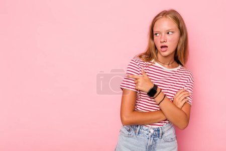 Foto de Caucásico adolescente chica aislado en rosa fondo puntos con el dedo pulgar de distancia, riendo y despreocupado. - Imagen libre de derechos
