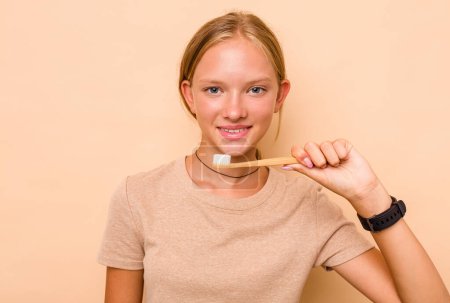 Téléchargez les photos : Caucasien adolescent fille brossage dents isolé sur beige fond - en image libre de droit