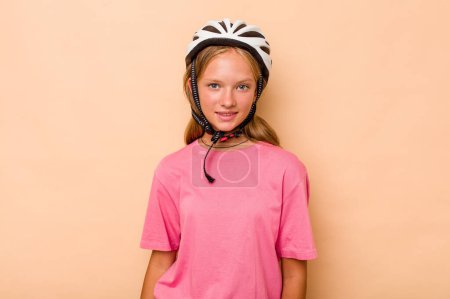 Téléchargez les photos : Petite fille caucasienne portant un casque de vélo isolé sur fond beige heureux, souriant et joyeux. - en image libre de droit