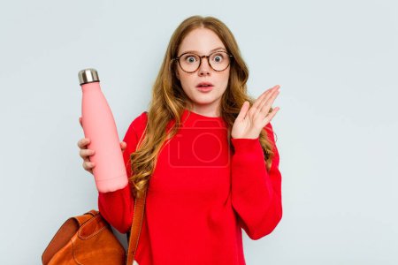 Photo for Young student woman holding a canteen isolated on blue background surprised and shocked. - Royalty Free Image