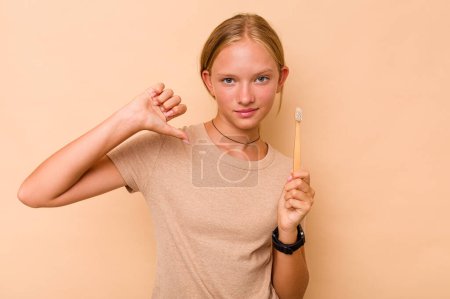 Foto de Caucásico adolescente chica cepillarse los dientes aislados en beige fondo se siente orgulloso y seguro de sí mismo, ejemplo a seguir. - Imagen libre de derechos
