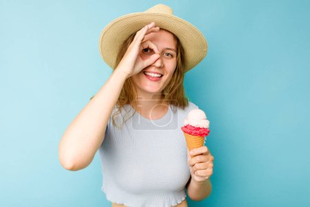 Photo for Young caucasian woman holding an ice cream isolated a blue background excited keeping ok gesture on eye. - Royalty Free Image