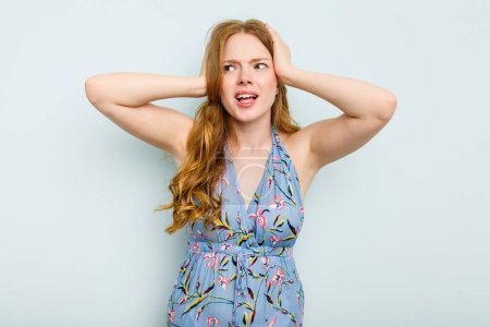Photo for Young caucasian woman isolated on blue background covering ears with hands trying not to hear too loud sound. - Royalty Free Image