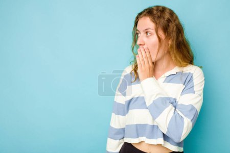 Photo for Young caucasian woman isolated on blue background being shocked because of something she has seen. - Royalty Free Image