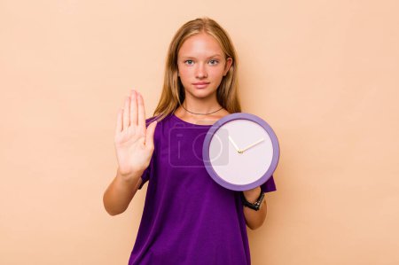 Photo for Little caucasian girl holding a clock isolated on beige background standing with outstretched hand showing stop sign, preventing you. - Royalty Free Image