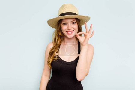 Photo for Young caucasian woman going to the beach isolated on blue background cheerful and confident showing ok gesture. - Royalty Free Image