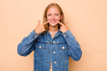 Téléchargez les photos : Caucasien adolescent fille isolé sur beige fond sourit pointant doigt à bouche. - en image libre de droit