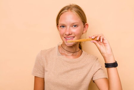Téléchargez les photos : Caucasien adolescent fille brossage dents isolé sur beige fond - en image libre de droit