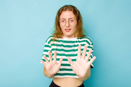Photo for Young caucasian woman isolated on blue background rejecting someone showing a gesture of disgust. - Royalty Free Image