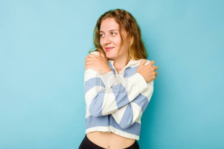 Téléchargez les photos : Jeune femme caucasienne isolée sur fond bleu câlins, souriant insouciant et heureux. - en image libre de droit
