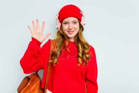 Téléchargez les photos : Jeune étudiante femme portant des écouteurs isolés sur fond bleu souriant gai montrant numéro cinq avec les doigts. - en image libre de droit