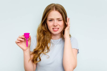Téléchargez les photos : Jeune femme caucasienne tenant la coupe menstruelle isolée sur fond bleu couvrant les oreilles avec les mains. - en image libre de droit